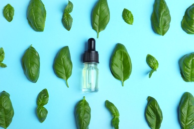 Flat lay composition with basil essential oil on light blue background