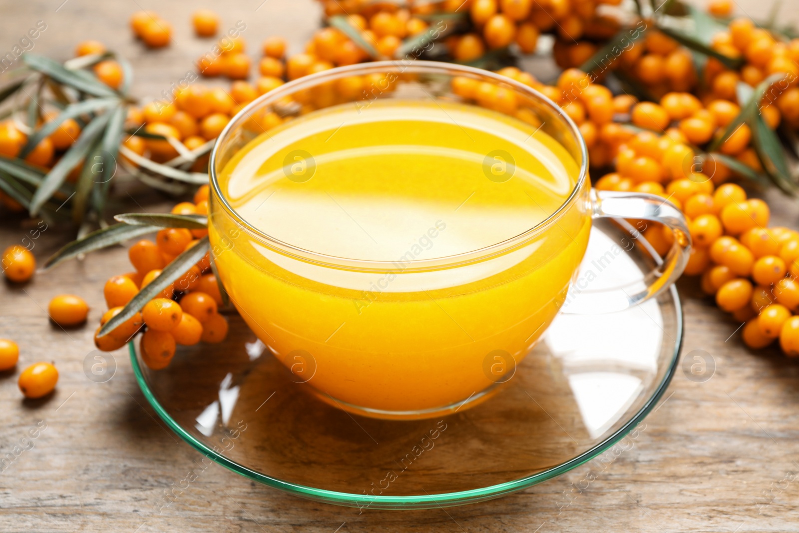 Photo of Fresh sea buckthorn tea on wooden table, closeup