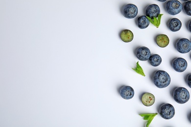 Photo of Tasty ripe blueberries and leaves on white background, flat lay