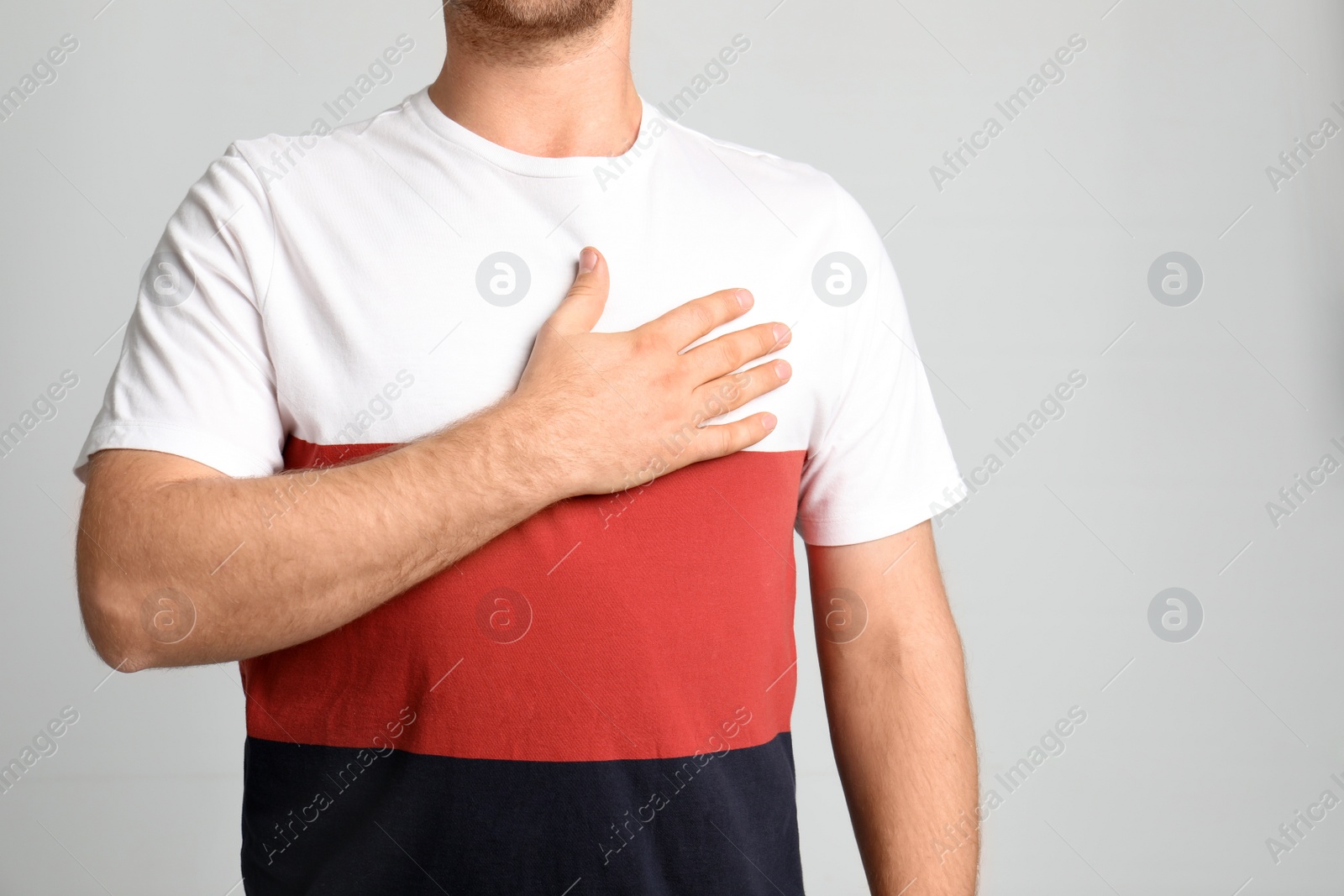 Photo of Man holding hand near heart on light background, closeup