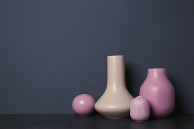 Photo of Beautiful ceramic vases on table against color wall with space for text