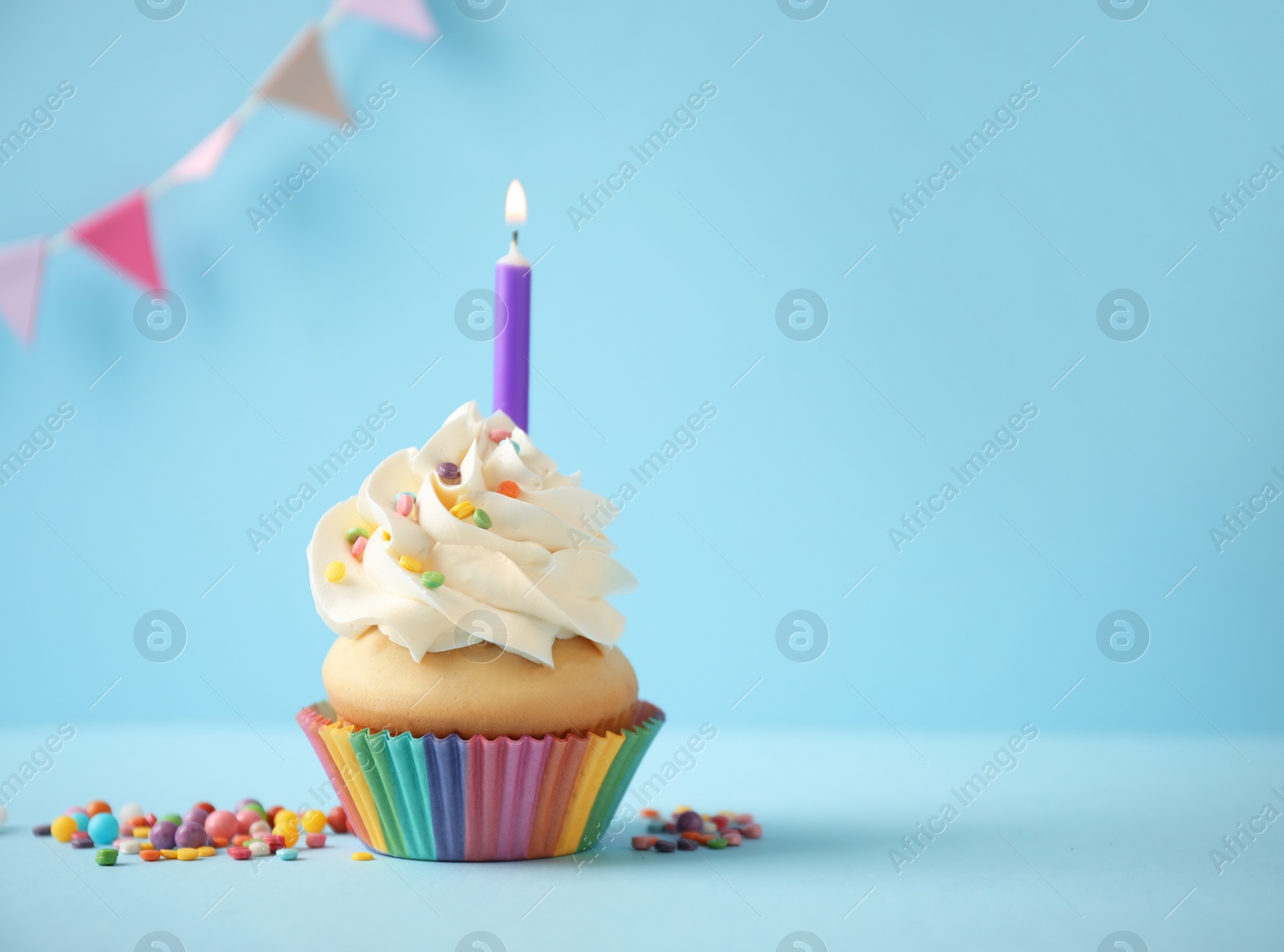 Photo of Delicious birthday cupcake with candle on light blue background. Space for text