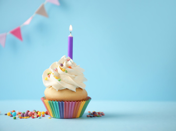 Delicious birthday cupcake with candle on light blue background. Space for text