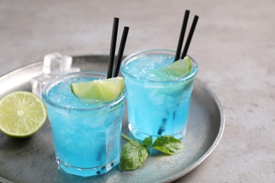 Photo of Tasty fresh light blue drink with lime on grey table