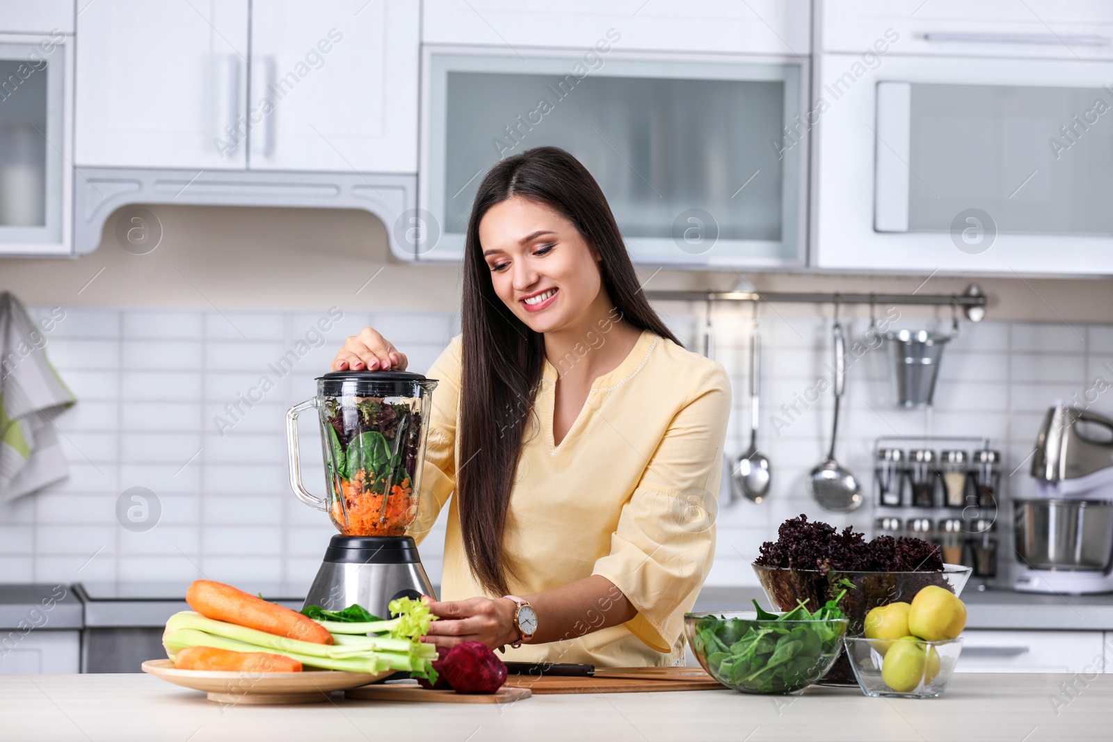 Photo of Young woman preparing tasty healthy smoothie at table in kitchen