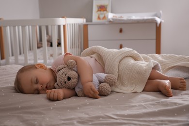 Photo of Adorable little baby with toy bear sleeping on bed at home