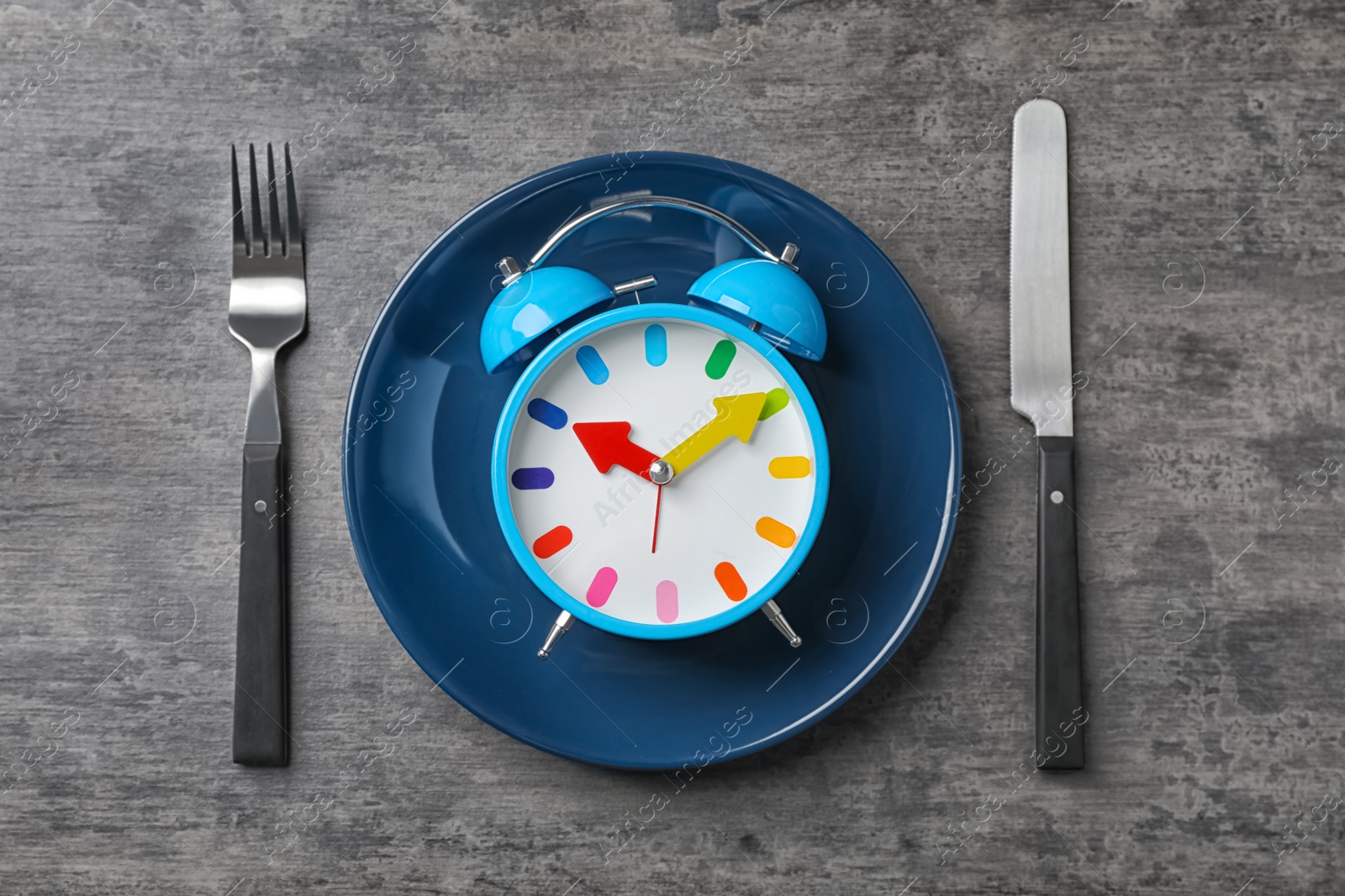 Photo of Flat lay composition with alarm clock, plate and utensils on grey background