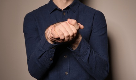 Photo of Man showing BELIEVE gesture in sign language on color background, closeup