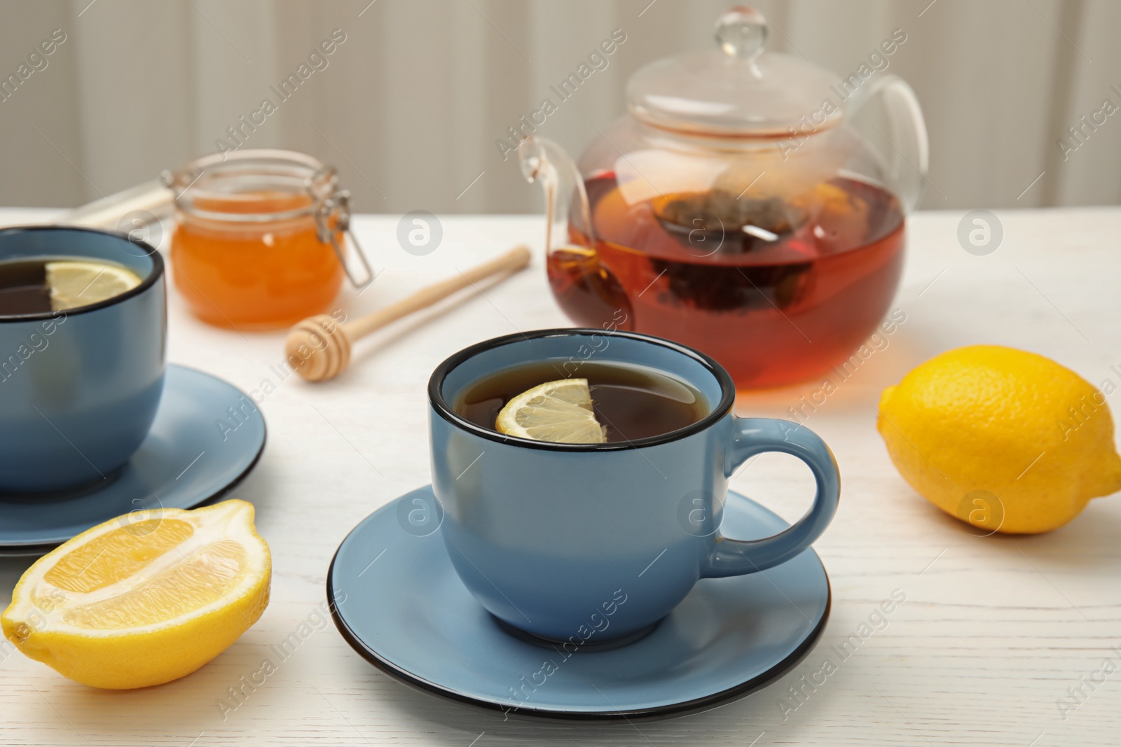 Photo of Cup with black tea and lemon on table