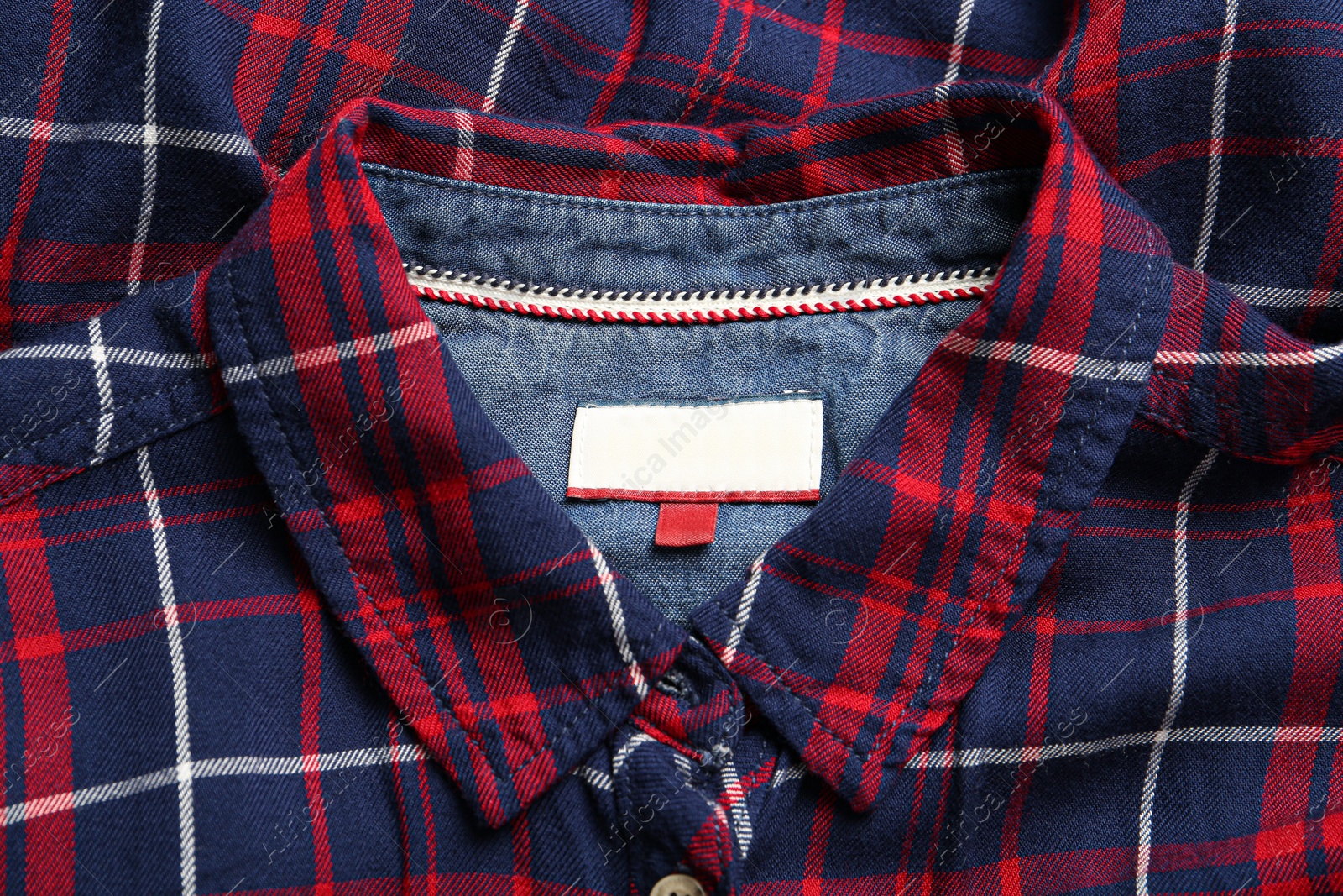 Photo of Blank clothing label on checkered shirt, top view