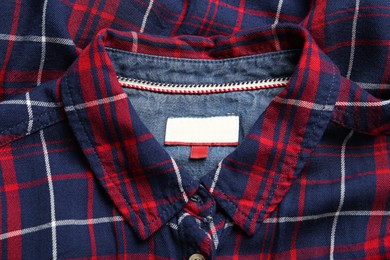 Photo of Blank clothing label on checkered shirt, top view