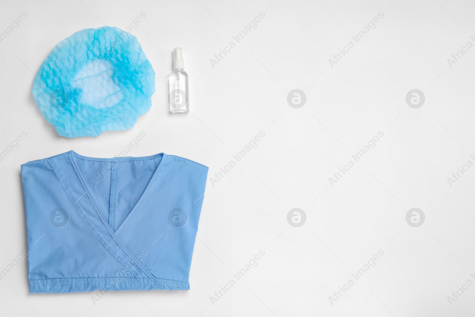 Photo of Medical uniform, cap and antiseptic on white background, flat lay. Space for text