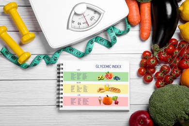 Image of Information about grouping of products under their glycemic index. Notebook, measuring tape, fruits, vegetables, dumbbells and floor scale on white wooden table, flat lay