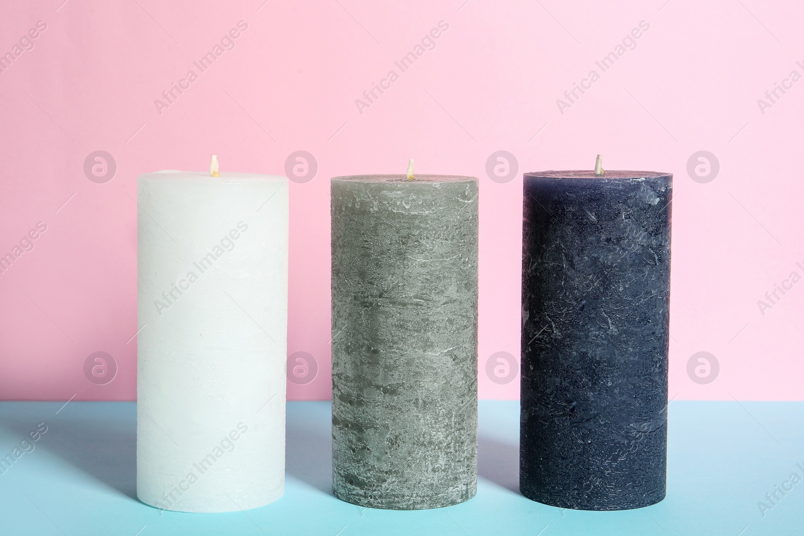 Photo of Decorative wax candles on table against color background