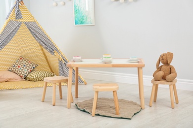 Photo of Cozy kids room interior with table, play tent and toys