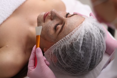 Photo of Cosmetologist applying mask on woman's face in clinic, closeup