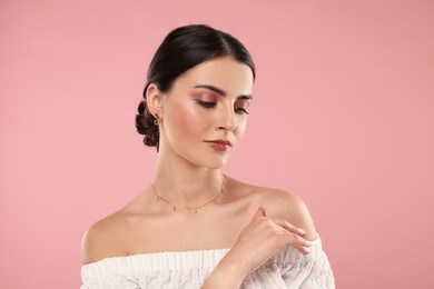 Beautiful woman with elegant jewelry on pink background