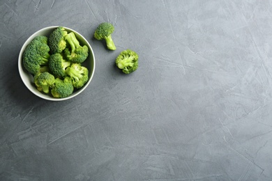 Photo of Bowl and fresh broccoli on grey table, flat lay with space for text