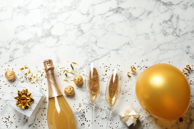 Flat lay composition with bottle of champagne for celebration on white marble background. Space for text