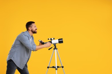 Photo of Happy astronomer with telescope on orange background. Space for text