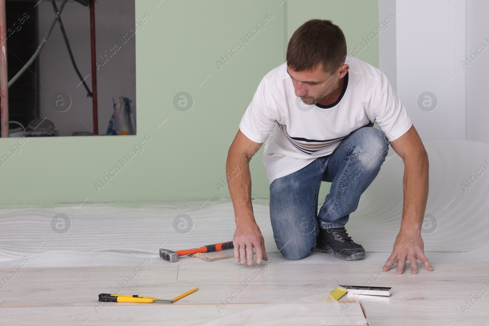 Photo of Man installing new laminate flooring in room