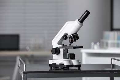 Photo of Modern medical microscope on metal table in laboratory