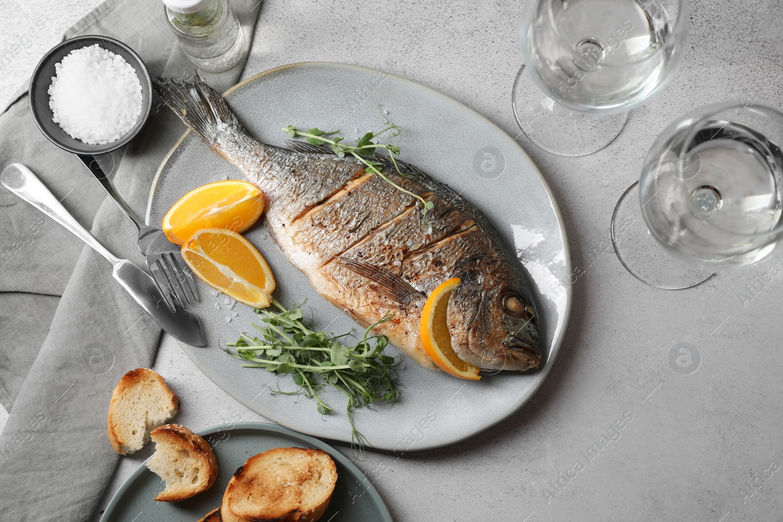 Photo of Seafood. Delicious baked fish served on grey textured table, flat lay