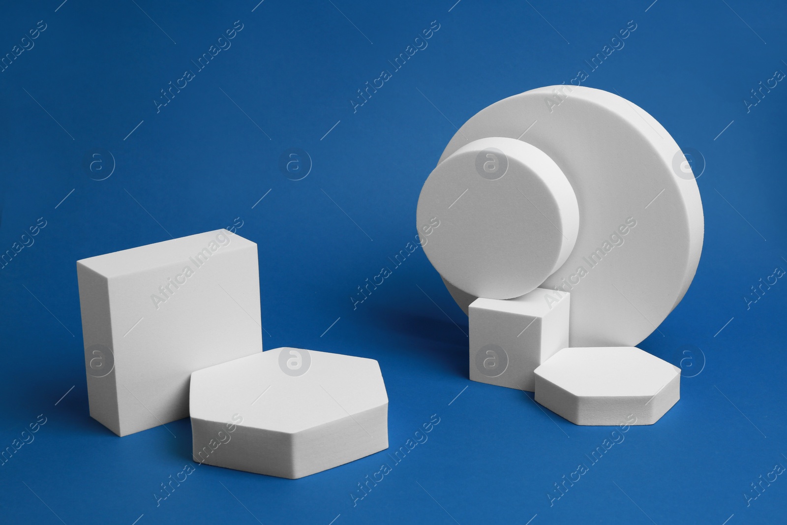 Photo of Product photography props. Podiums of different geometric shapes on blue background