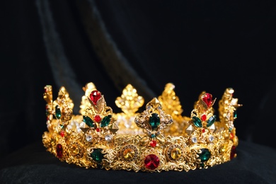 Photo of Beautiful golden crown on black fabric. Fantasy item