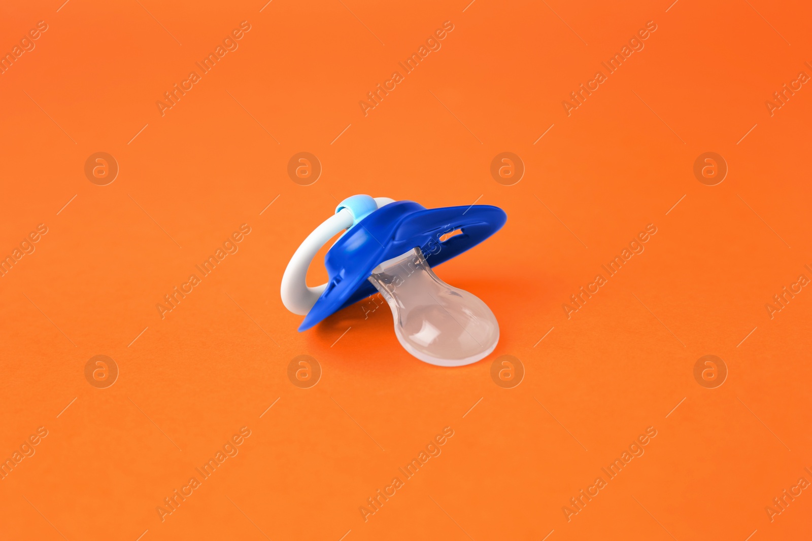 Photo of One blue baby pacifier on orange background