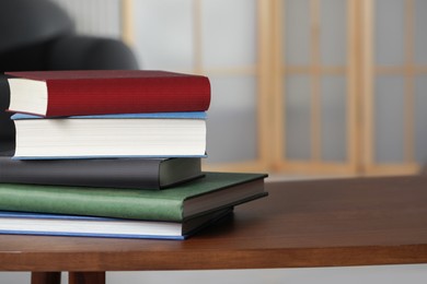 Photo of Stack of hardcover books on wooden coffee table indoors, space for text