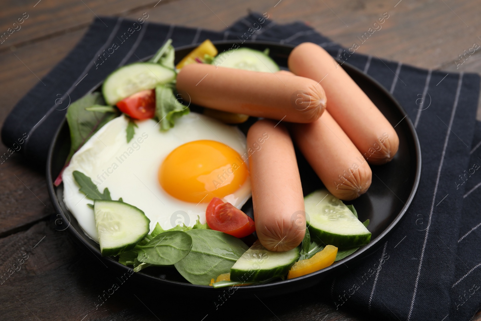 Photo of Delicious breakfast with boiled sausages and fried egg on wooden table, closeup