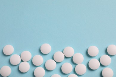 Photo of Many white pills on light blue background, flat lay. Space for text