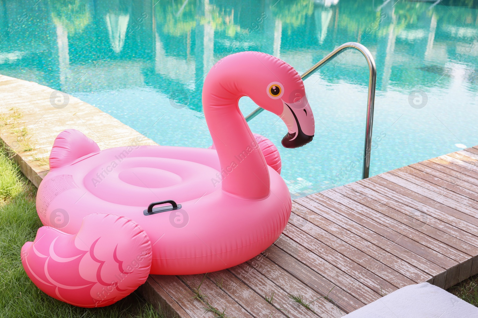 Photo of Float in shape of flamingo on wooden deck near swimming pool at luxury resort