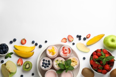 Photo of Tasty yogurt in glass jars and ingredients on white background, top view. Space for text