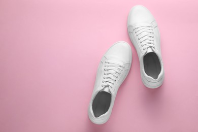 Pair of stylish white sneakers on pink background, top view. Space for text