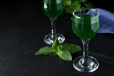 Photo of Delicious mint liqueur on black table. Space for text