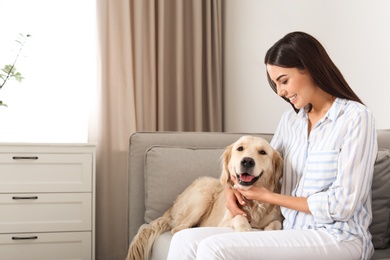 Young woman and her Golden Retriever dog in living room. Space for text