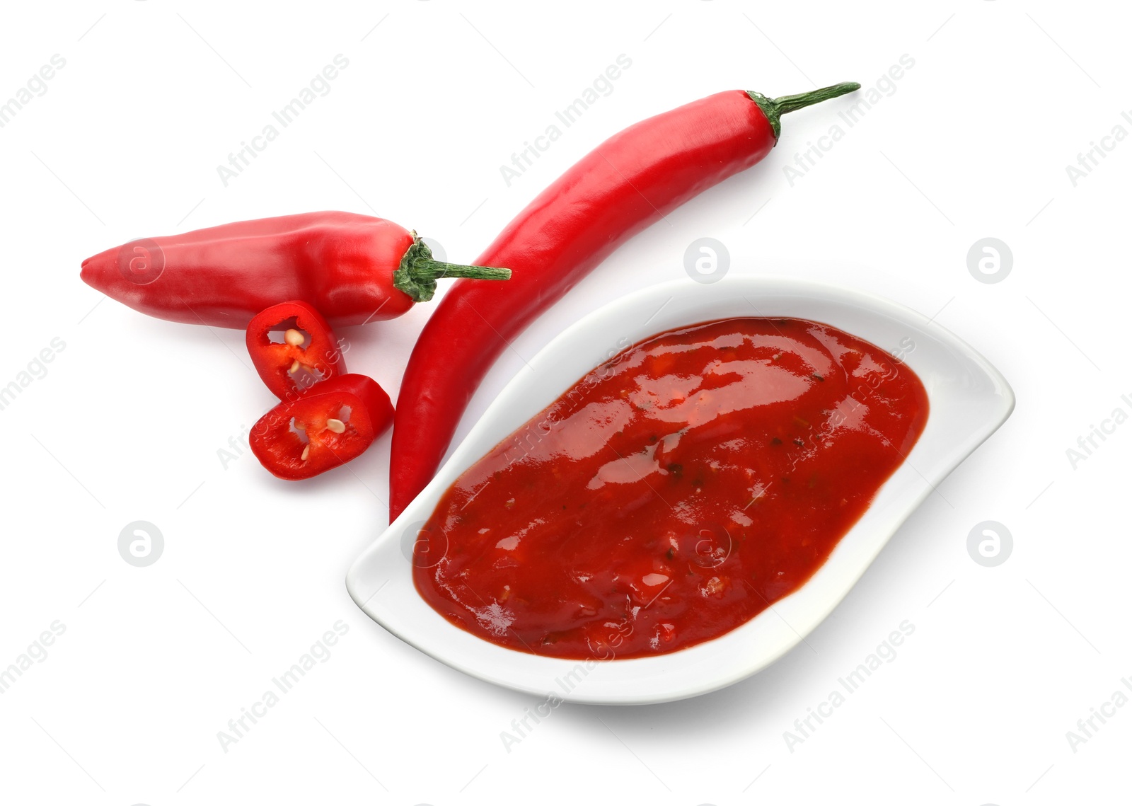 Photo of Gravy boat with spicy chili sauce and fresh pepper on white background, top view