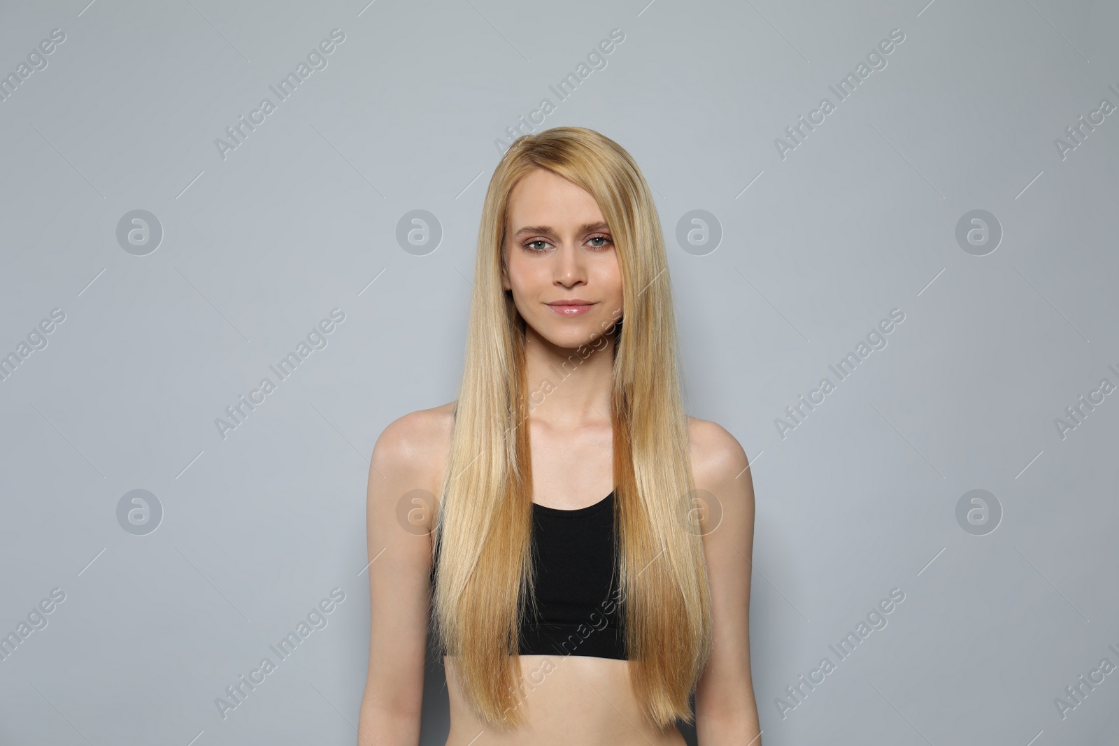 Photo of Beautiful young woman with long straight hair on grey background