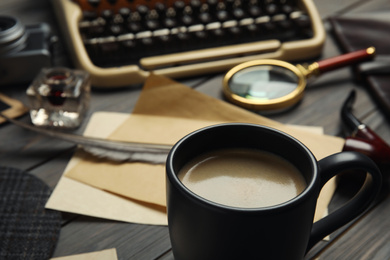 Composition with vintage detective items on grey wooden table, focus on cup of coffee