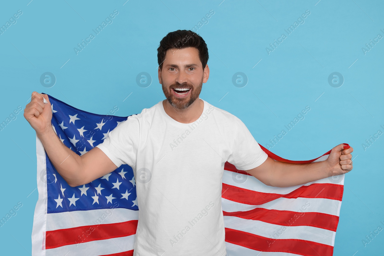Photo of 4th of July - Independence Day of USA. Happy man with American flag on light blue background