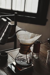 Photo of Pouring hot water into coffee maker at wooden table in cafe, closeup
