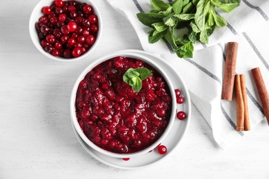 Photo of Flat lay composition with cranberry sauce in bowl on white wooden background