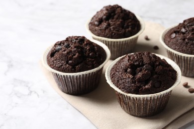Photo of Tasty chocolate muffins on white marble table, space for text