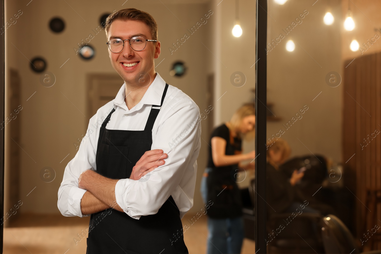 Photo of Portrait of professional hairdresser wearing apron in beauty salon