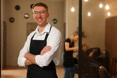 Portrait of professional hairdresser wearing apron in beauty salon