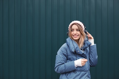 Photo of Young woman with headphones listening to music near color wall. Space for text