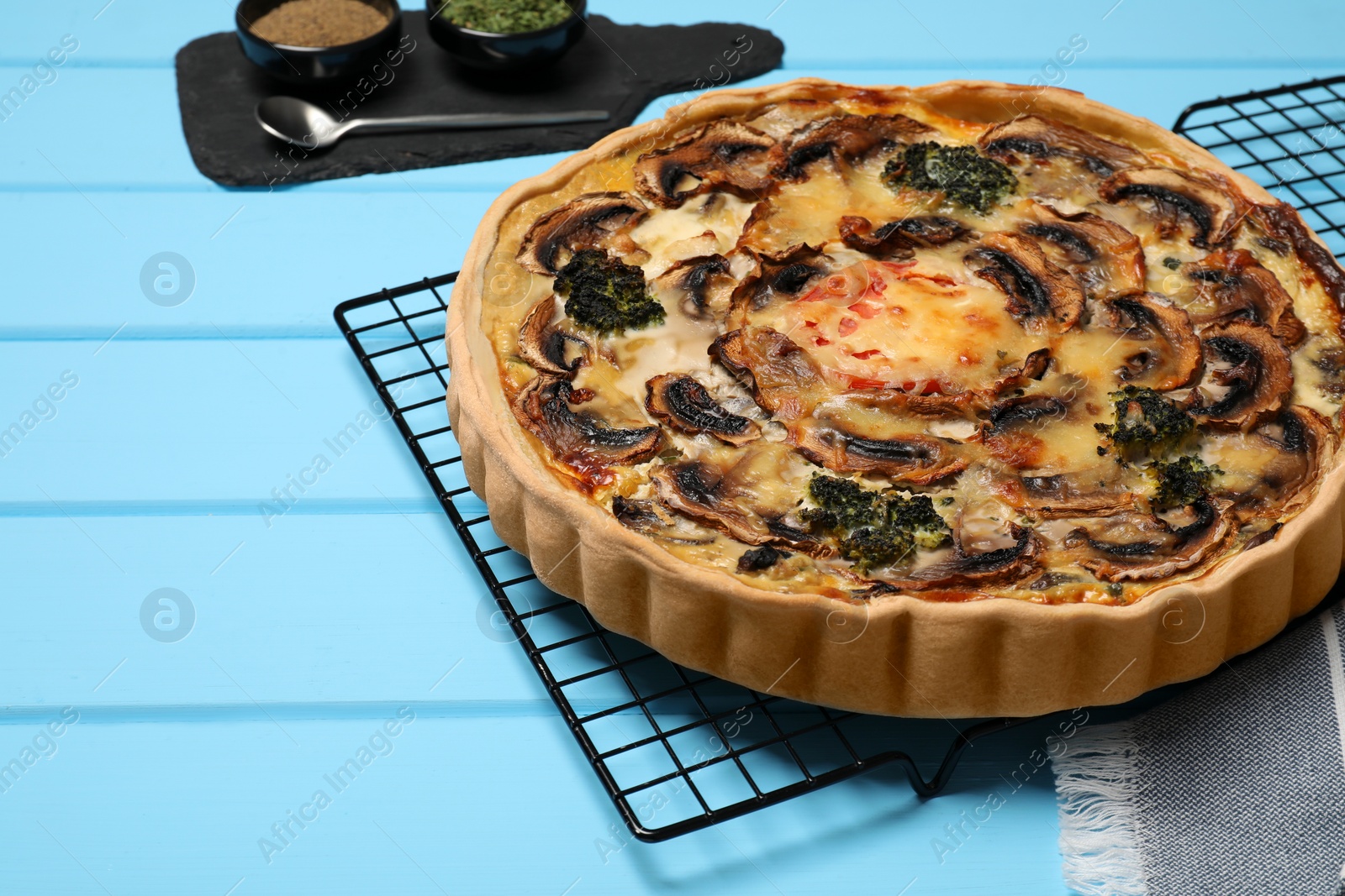 Photo of Delicious quiche with mushrooms on light blue wooden table