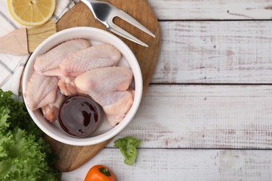 Photo of Flat lay composition with marinade, raw chicken wings and other products on rustic wooden table. Space for text